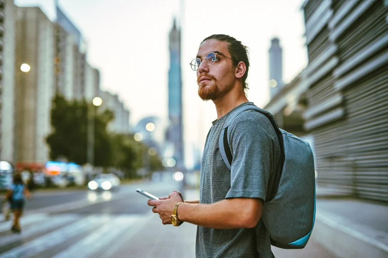 Junger Mann mit Handy & Rucksack - hier ein Anspruchsinhaber für eine Prozessfinanzierung