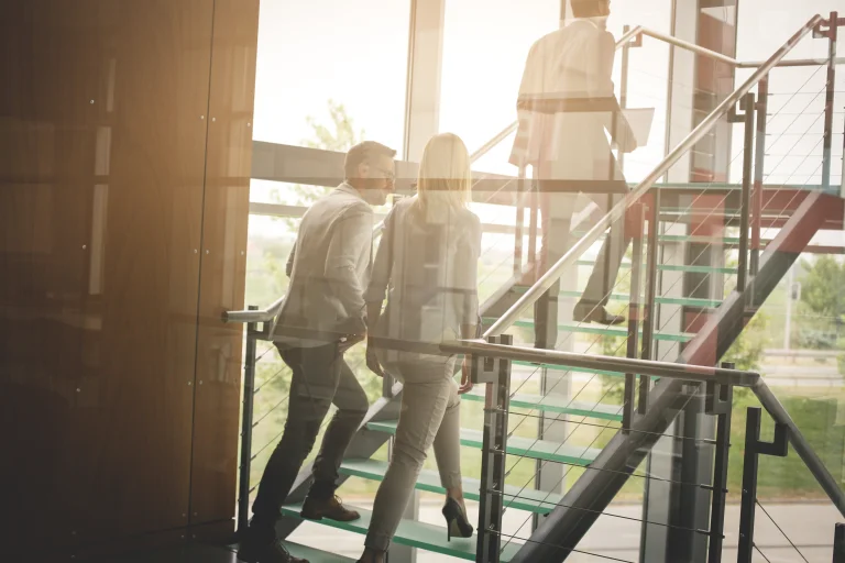 Bürogebäude von innen und drei Kollegen auf einer Treppe als Beispiel für KMU