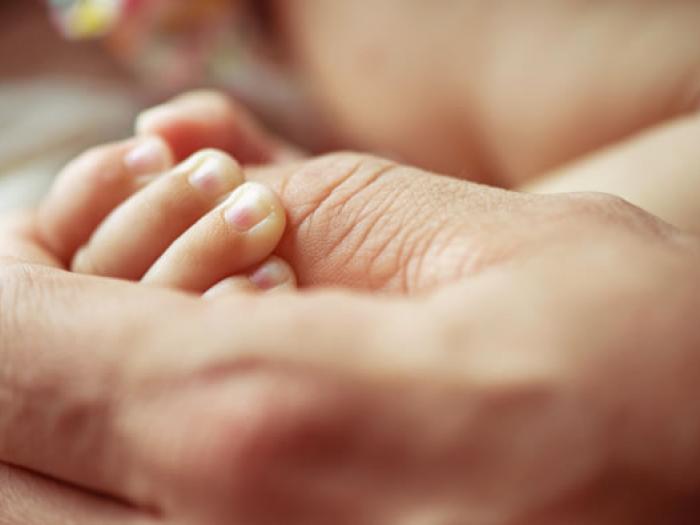 Erwachsene Person hält Hand von Säugling, Arzthaftungsrecht
